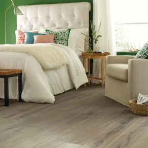 Gray-toned hardwood in a bedroom with a white tufted headboard | Shoreline Flooring