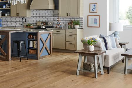 Warm wood flooring in an open-concept kitchen and living room with comfortable seating | Shoreline Flooring